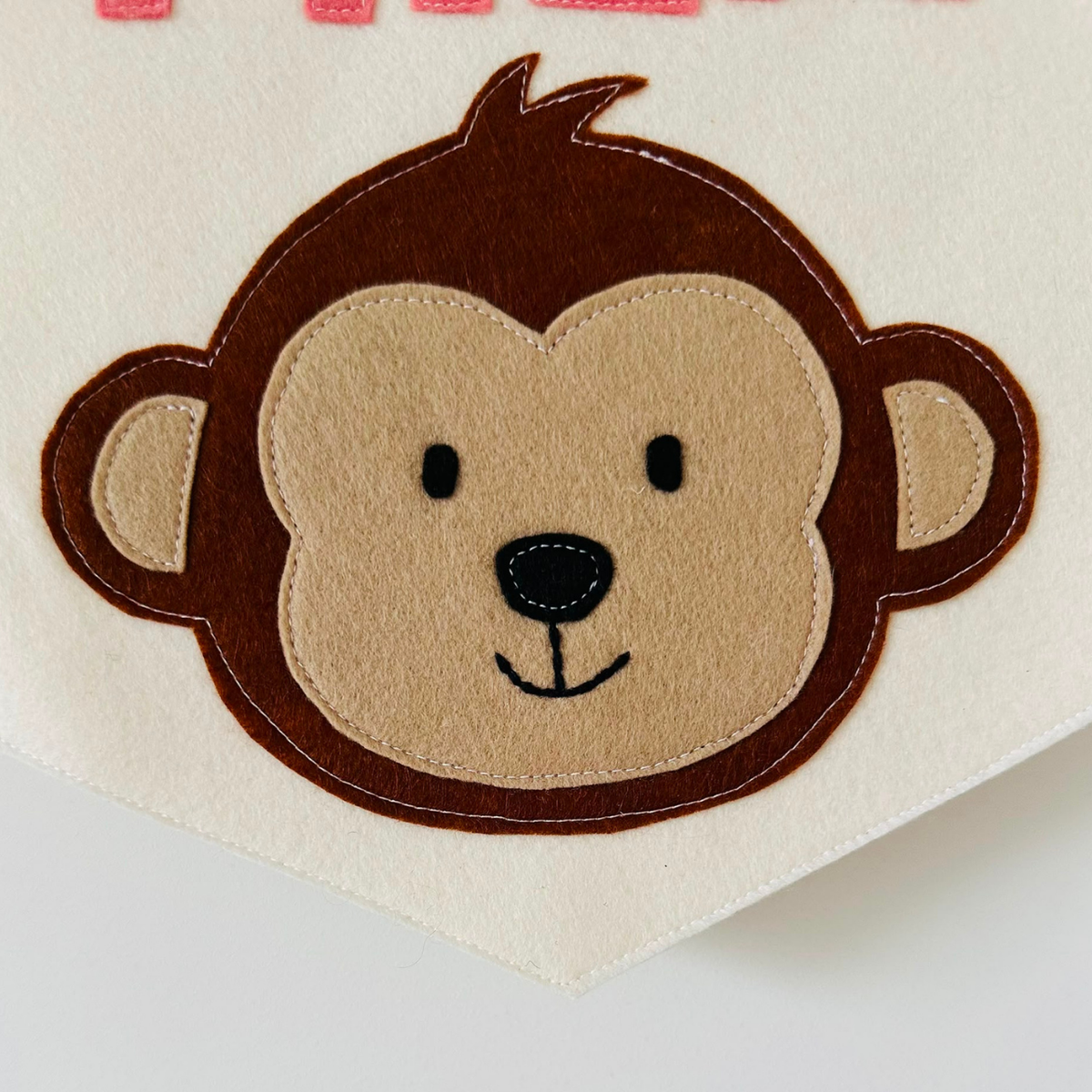 Gepersonaliseerde handgemaakte vilten banner met een aap icoon.