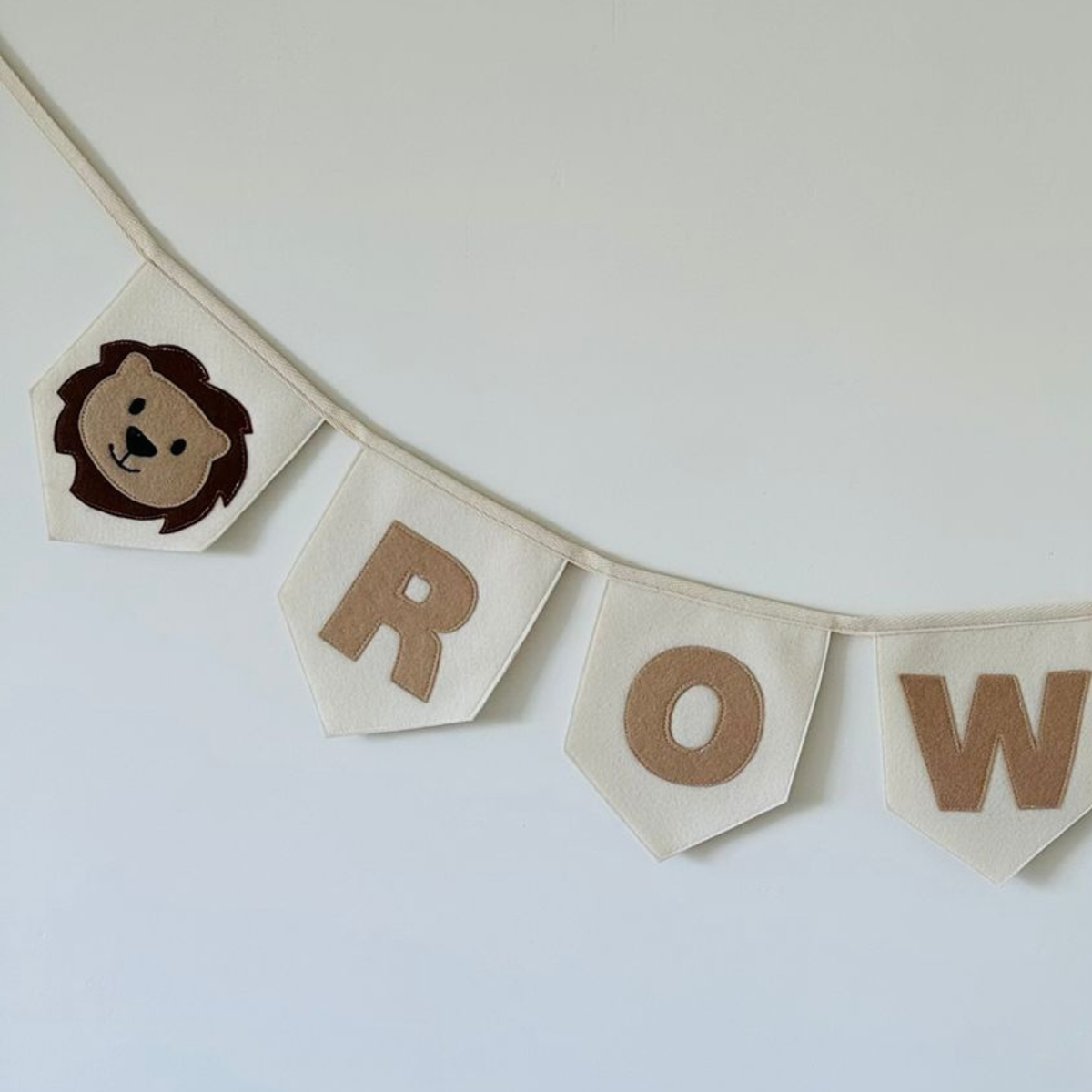 een close up van de jungle vlaggenlijn met aan de uiteinde het leeuwen incoon op champagne kleurige vlaggen met de letters ROW in beige kleur.