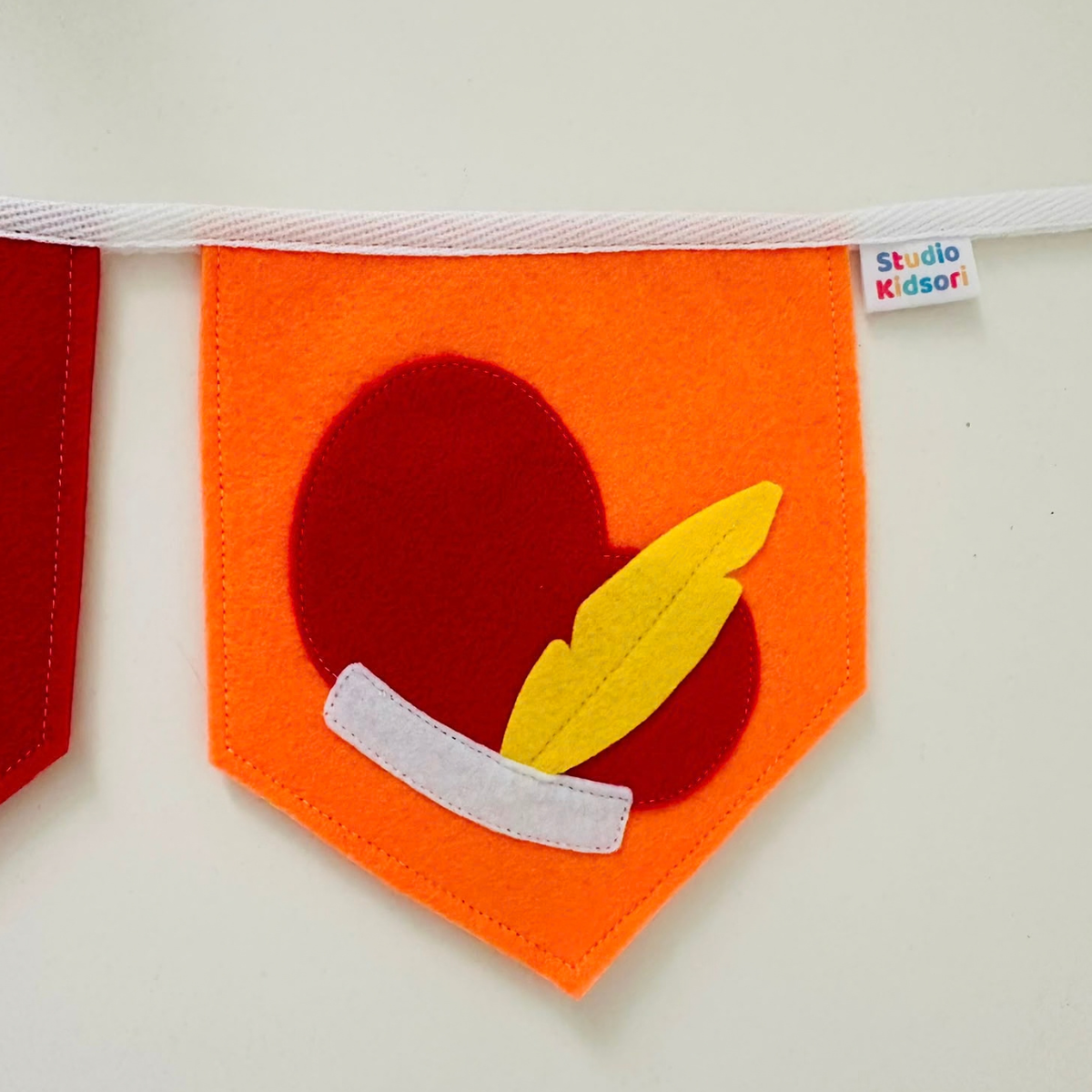 Vilten vlaggetje met Pietenmuts met gele veer op een oranje vlaggetje, onderdeel van de Sinterklaas vlaggenlijn SINT & PIET